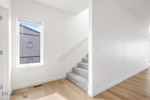 stairway featuring visible vents, baseboards, and wood finished floors