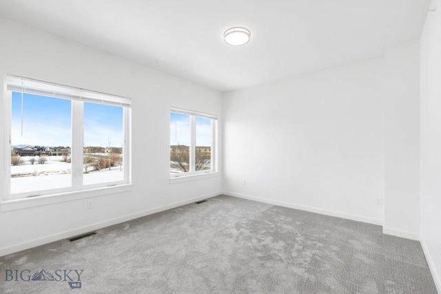 carpeted spare room with visible vents and baseboards