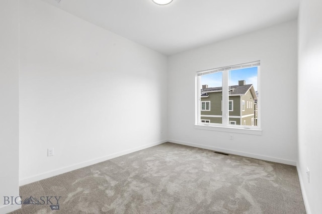 carpeted spare room with visible vents and baseboards