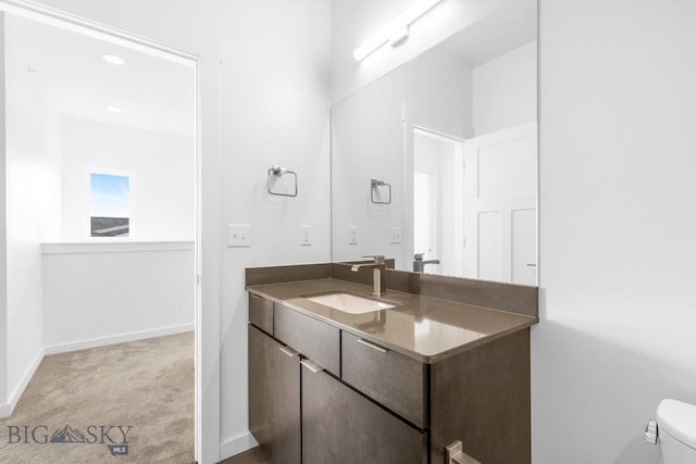 bathroom featuring toilet, vanity, and baseboards