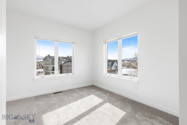 carpeted spare room featuring visible vents and baseboards