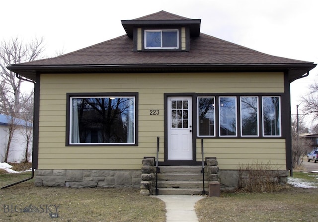 bungalow-style home with entry steps and roof with shingles