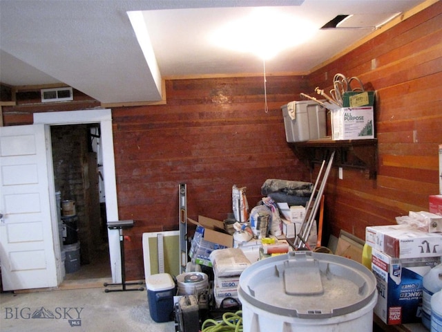 interior space featuring wooden walls, visible vents, and concrete flooring