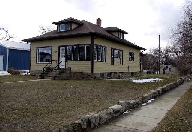 view of side of home with a yard, roof with shingles, and a chimney