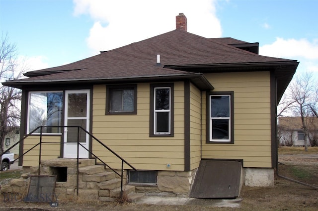 back of property featuring roof with shingles and a chimney