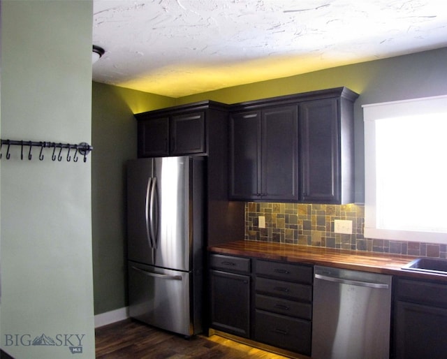 kitchen with stainless steel appliances, wooden counters, tasteful backsplash, and dark wood-style flooring