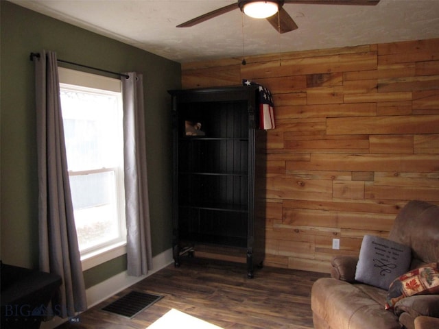 living room featuring a wealth of natural light, visible vents, and wood walls