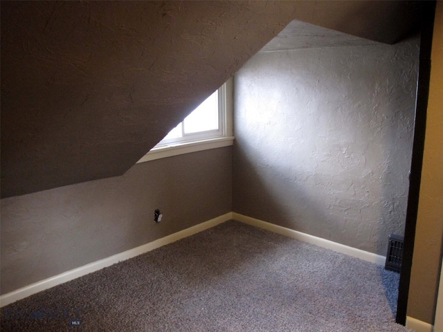 bonus room with baseboards, lofted ceiling, carpet, and a textured wall