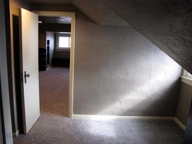 interior space with lofted ceiling, carpet, and a textured wall