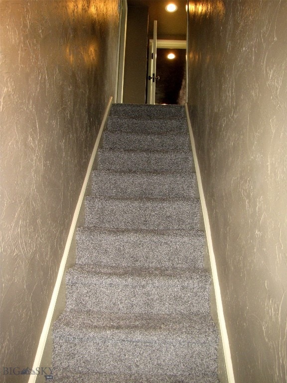 stairs featuring carpet floors and a textured wall