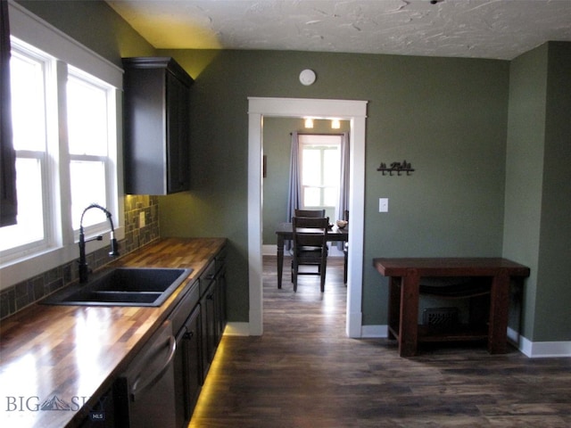 kitchen with dark wood-type flooring, tasteful backsplash, wooden counters, and a sink