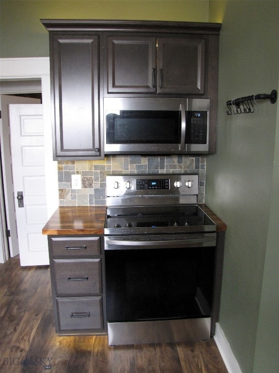 kitchen featuring tasteful backsplash, dark wood-type flooring, dark brown cabinetry, butcher block counters, and stainless steel appliances