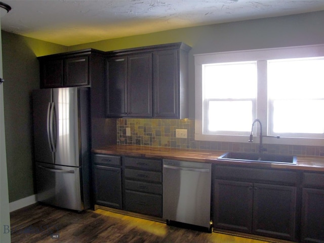 kitchen featuring dark wood-style flooring, appliances with stainless steel finishes, decorative backsplash, and a sink