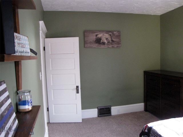 carpeted bedroom with visible vents, baseboards, and a textured ceiling