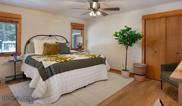 bedroom with baseboards, a baseboard heating unit, a ceiling fan, and wood finished floors