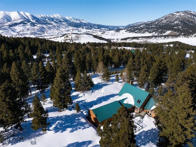 snowy aerial view featuring a mountain view and a forest view