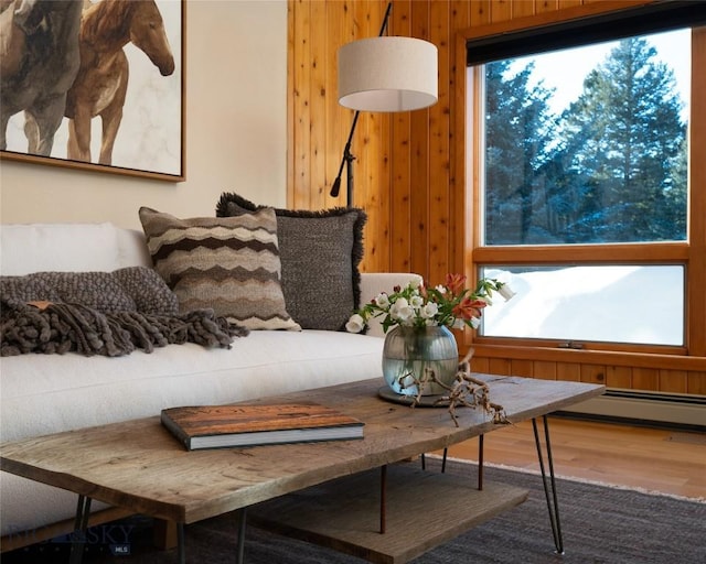 interior space with wooden walls, a baseboard heating unit, and wood finished floors