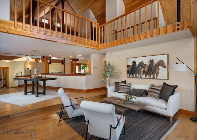 living room with hardwood / wood-style flooring, baseboards, and a towering ceiling