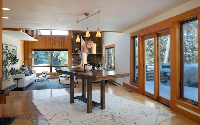 dining area with a fireplace, light wood-style floors, visible vents, and wood walls