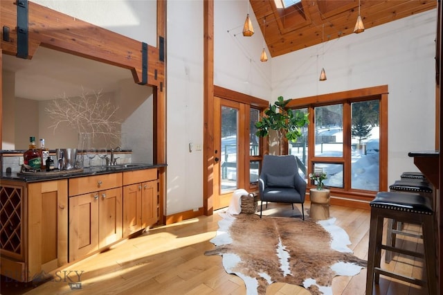 sitting room with light wood-style flooring, a skylight, and high vaulted ceiling