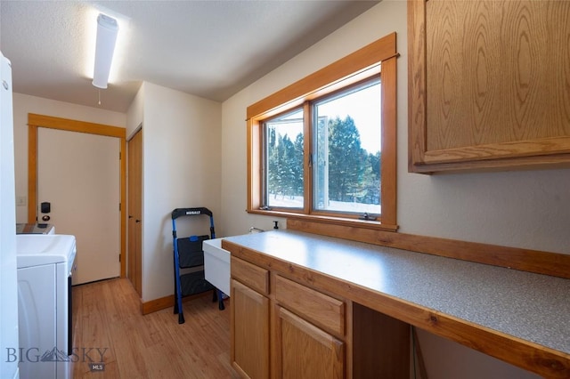 office area with baseboards, light wood-style floors, and separate washer and dryer