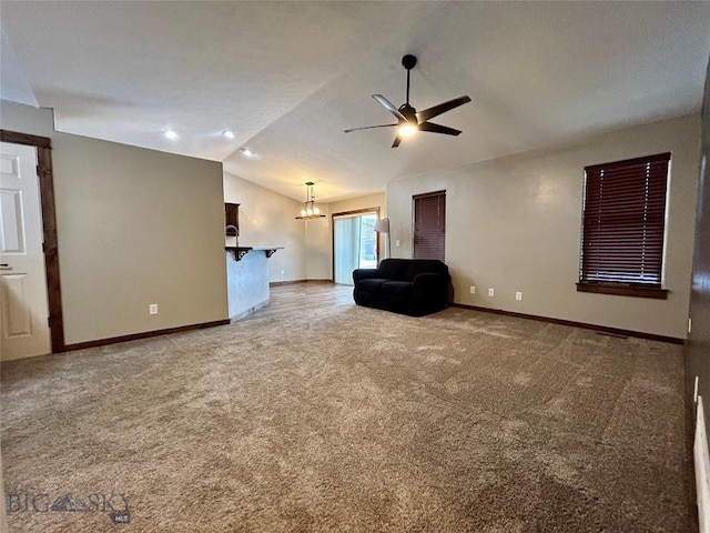 unfurnished living room with lofted ceiling, ceiling fan with notable chandelier, baseboards, and light carpet