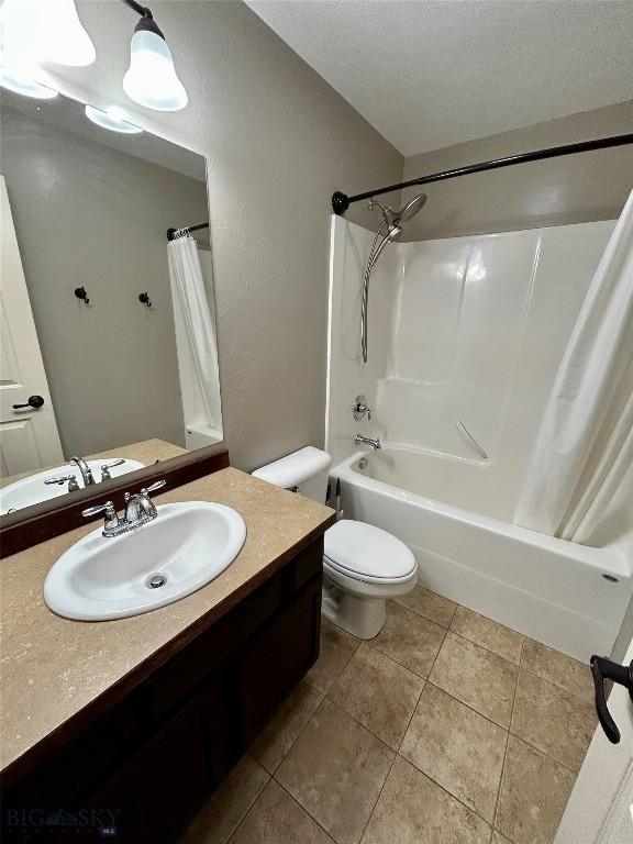 full bath featuring tile patterned flooring, toilet, shower / tub combo, a textured ceiling, and vanity