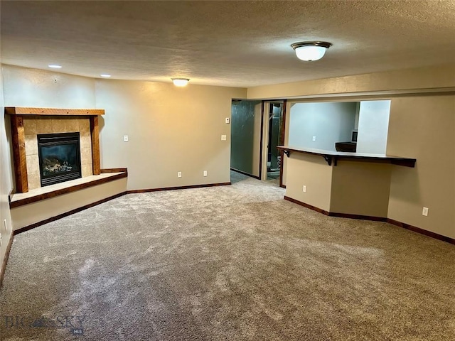 unfurnished living room featuring a fireplace, baseboards, carpet floors, and a textured ceiling