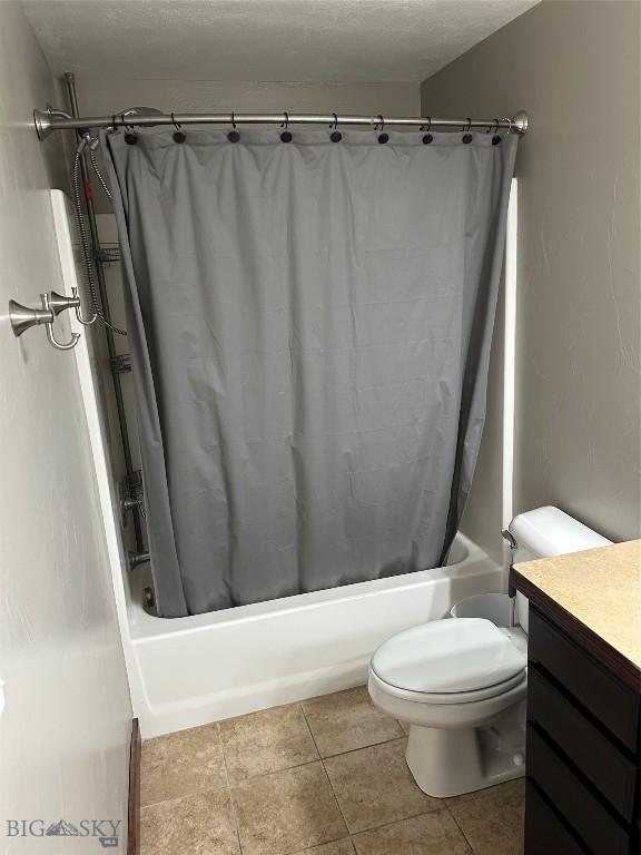 bathroom with tile patterned floors, shower / bath combination with curtain, toilet, and vanity