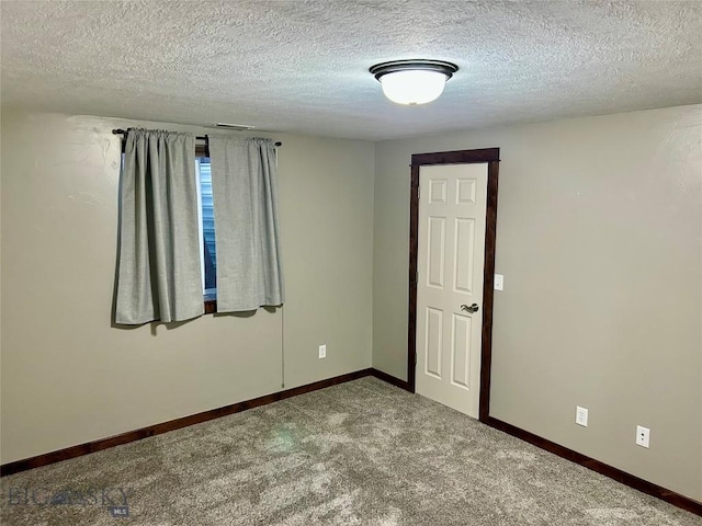 spare room featuring carpet flooring, baseboards, and a textured ceiling