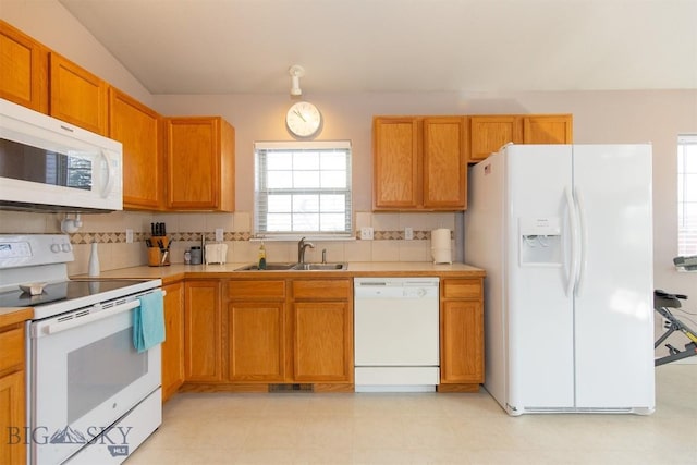 kitchen featuring visible vents, light countertops, decorative backsplash, white appliances, and a sink