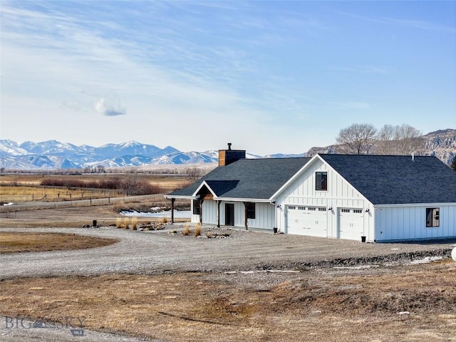 18287 Haasakker Rd, Three Forks, MT 59752 - view of front of property with a chimney, a mountain view, board and batten siding, a shingled roof, and dirt driveway