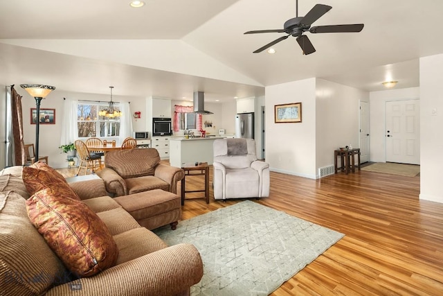 living area featuring baseboards, lofted ceiling, recessed lighting, light wood-style flooring, and ceiling fan with notable chandelier