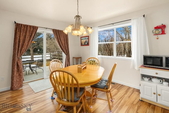 dining space featuring light wood-type flooring, baseboards, and a notable chandelier