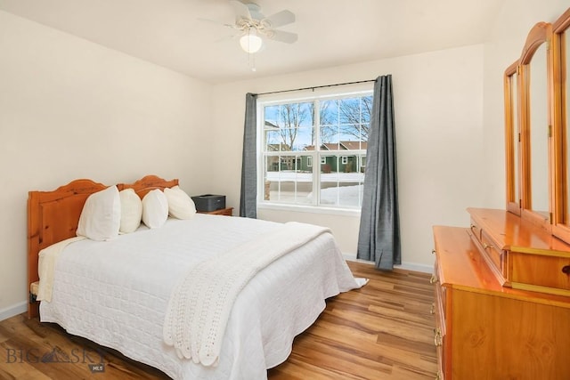 bedroom with ceiling fan, light wood-type flooring, and baseboards