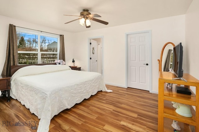 bedroom featuring light wood finished floors, a ceiling fan, and baseboards