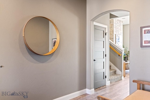 corridor with stairs, wood finished floors, and baseboards