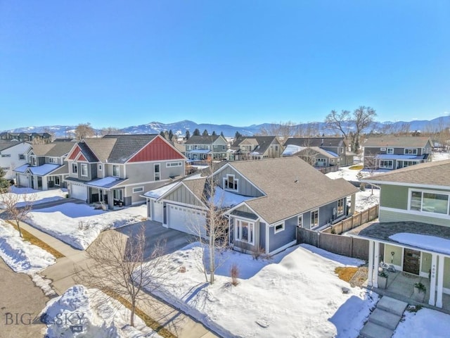 snowy aerial view with a mountain view and a residential view