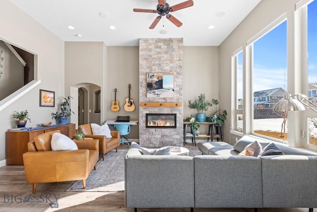 living room featuring arched walkways, recessed lighting, a fireplace, and wood finished floors