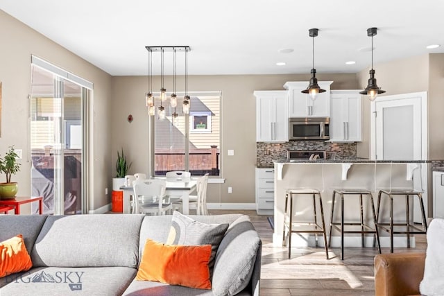 living area with recessed lighting, baseboards, and wood finished floors