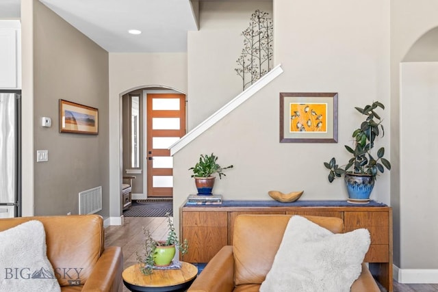 entryway featuring wood finished floors, arched walkways, and visible vents