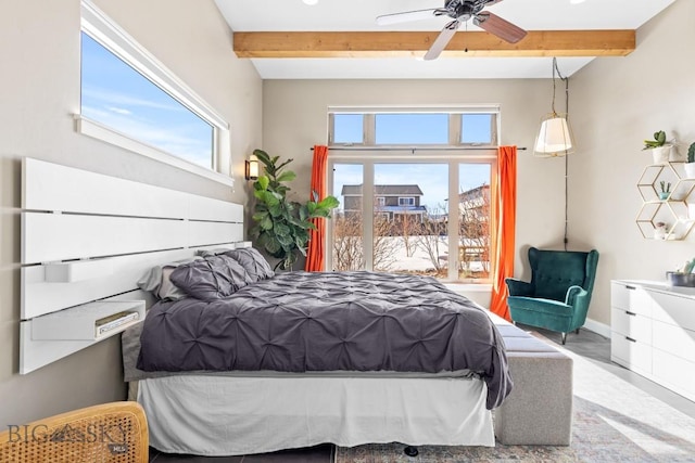 bedroom featuring beam ceiling, multiple windows, and baseboards