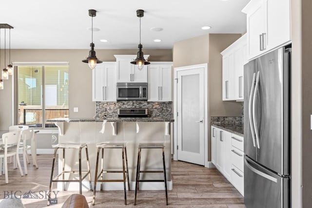 kitchen with tasteful backsplash, a breakfast bar, light wood-style flooring, white cabinets, and stainless steel appliances