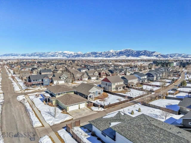 snowy aerial view with a mountain view and a residential view