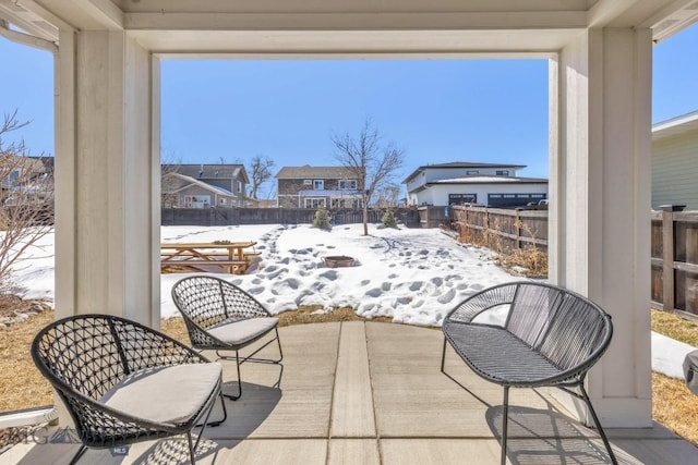 snow covered patio with a fenced backyard