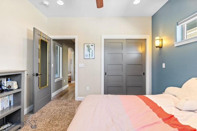 carpeted bedroom with recessed lighting, a closet, arched walkways, and baseboards