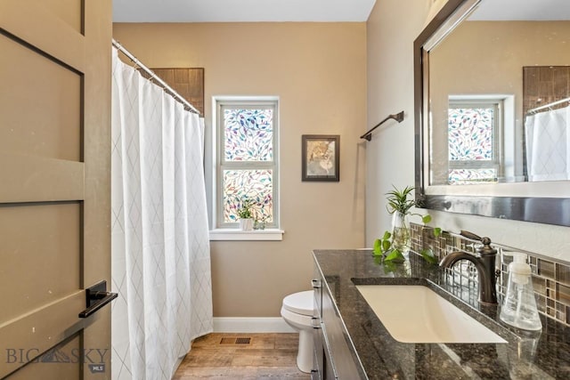 full bath featuring toilet, a healthy amount of sunlight, wood finished floors, and vanity