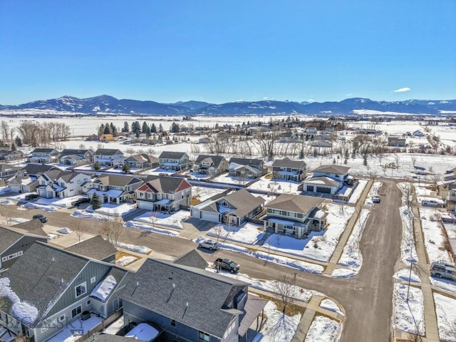 snowy aerial view with a mountain view and a residential view