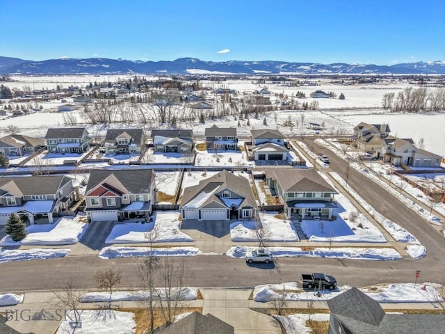 snowy aerial view with a mountain view and a residential view