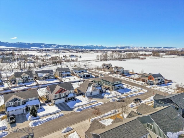 snowy aerial view with a mountain view and a residential view